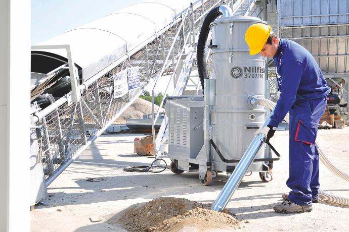 Operator using an industrial vacuum system for dust extraction in a mining processing area